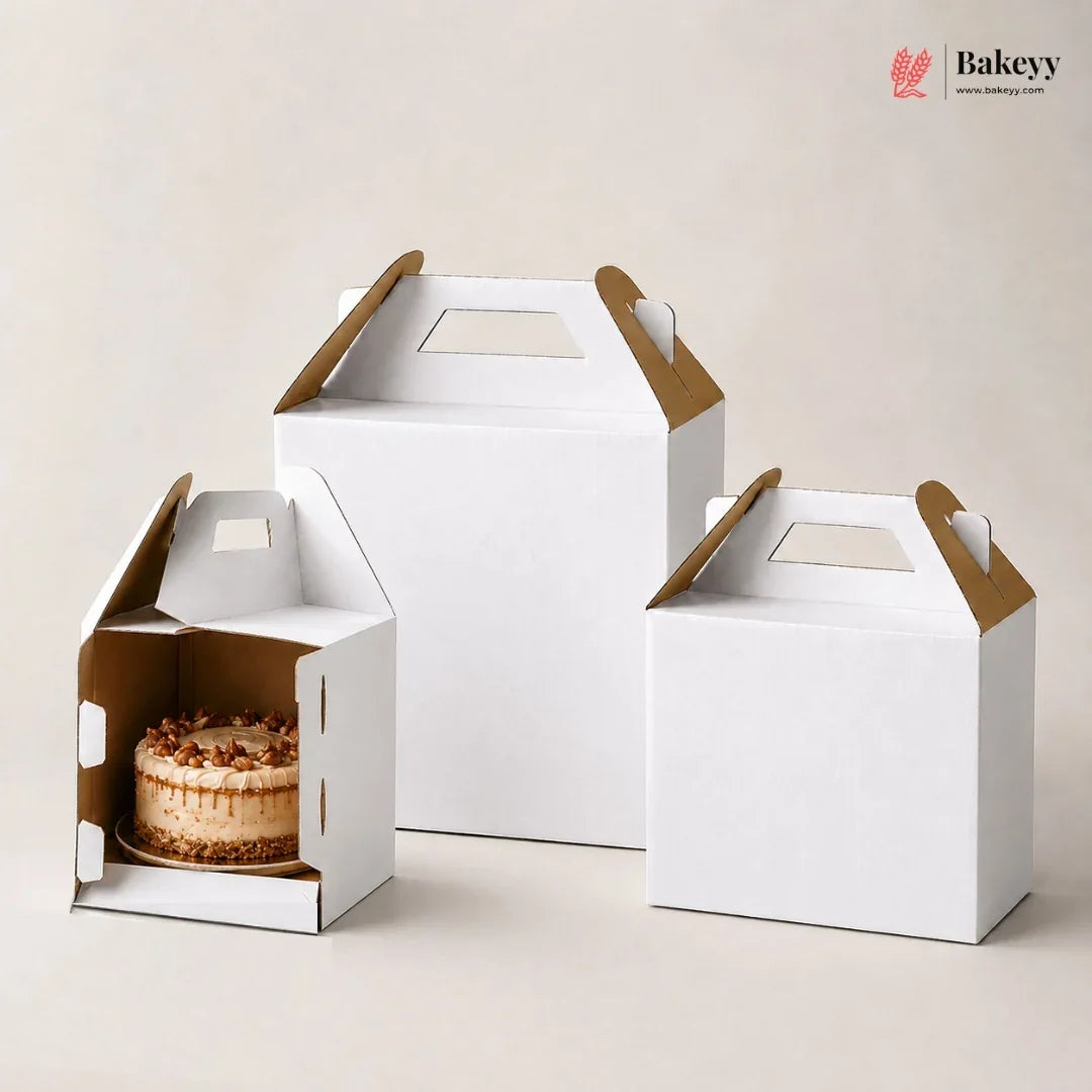 Three white cake boxes with brown handles on a light background, featuring the Bakeyy brand.