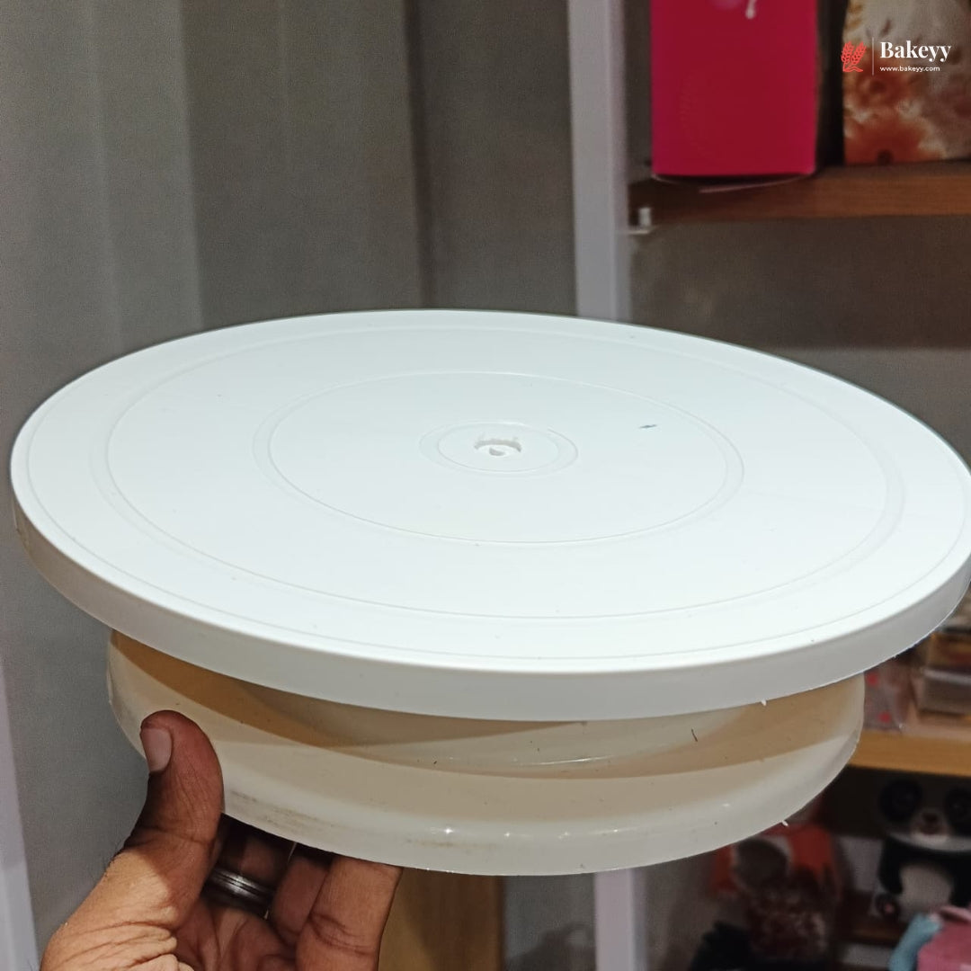 White round cake stand held by a hand with a blurred background