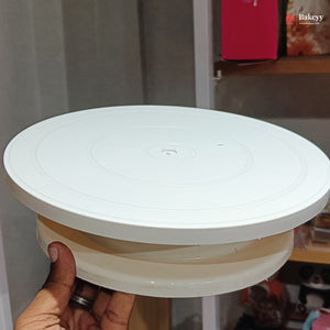 White round cake stand held by a hand with a blurred background