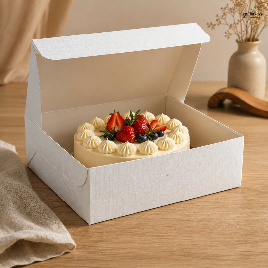 Small cake with strawberries and cream in a white box on a wooden table.