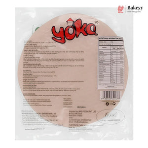 Back view of a packaged round rice cake on a white background, showing the Bakeyy logo, product details, nutrition facts, and a barcode. The package is clear plastic with printed text and branding.