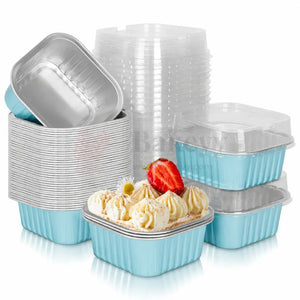 A set of light blue and silver disposable food containers, including square aluminum trays and clear plastic lids, arranged on a white background with a decorated dessert in the foreground.