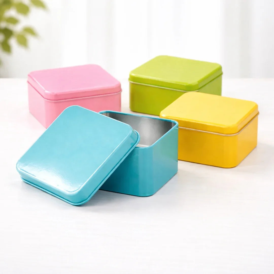 Colorful square tin boxes for gift packaging and baking supplies on a white table