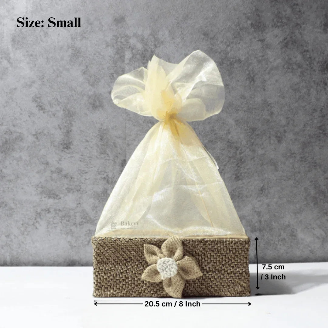 Small jute net hamper basket with cream organza wrap and flower accent, ideal for gift packaging from Bakeyy.com.