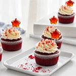 Red velvet cupcakes with cream cheese frosting and star-shaped toppers on a white plate.