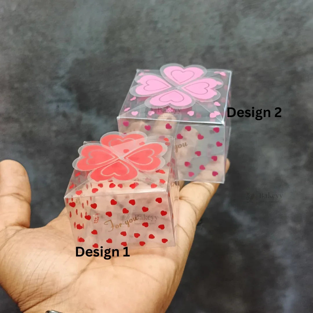 Two transparent heart-patterned gift boxes for bakery packaging, displayed on a hand.