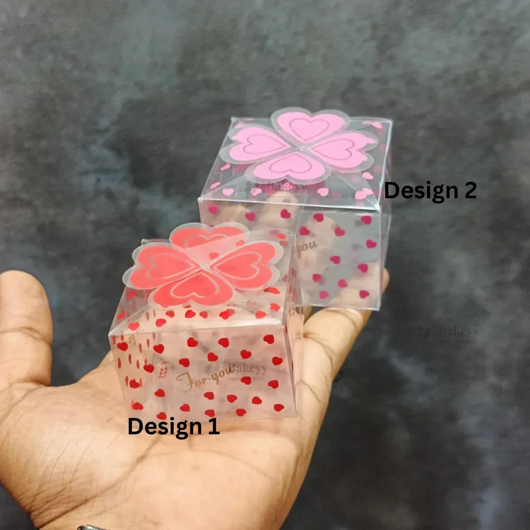 Two transparent heart-patterned gift boxes for bakery packaging, displayed on a hand.