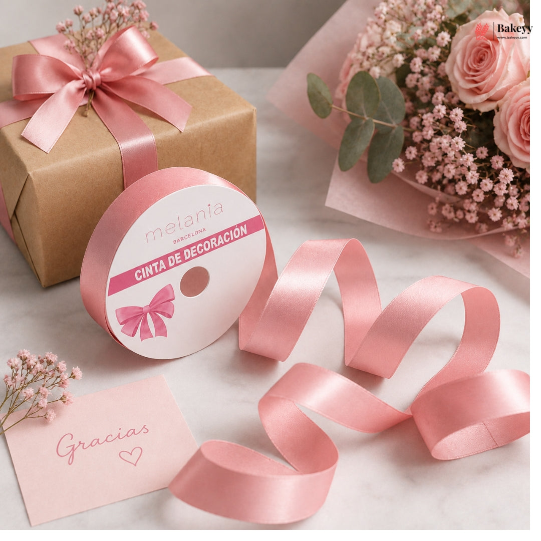 Pink ribbon with decorative packaging, flowers, and a card on a light surface