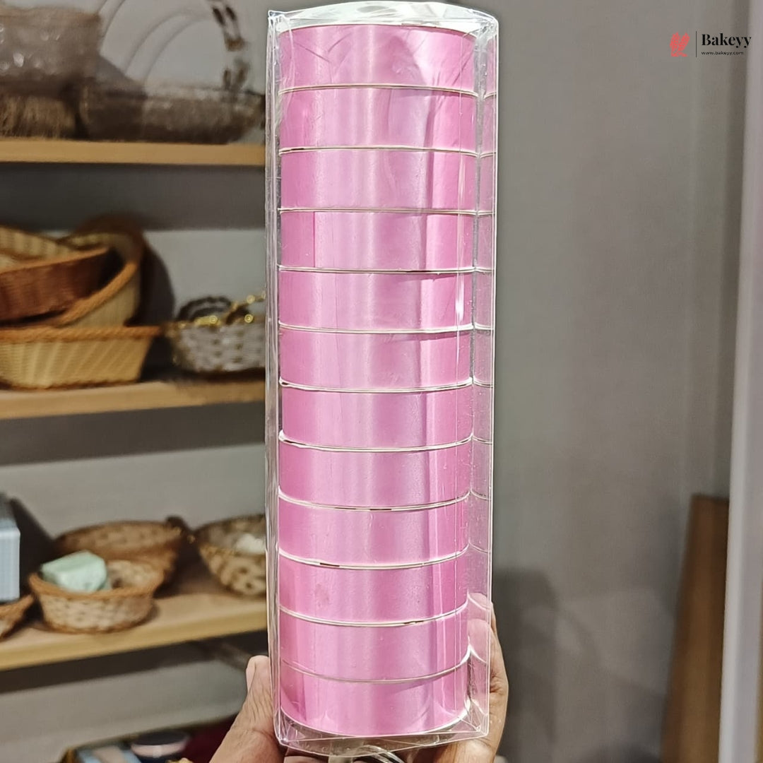 Roll of pink ribbon in clear packaging held in front of a shelf with wicker baskets.