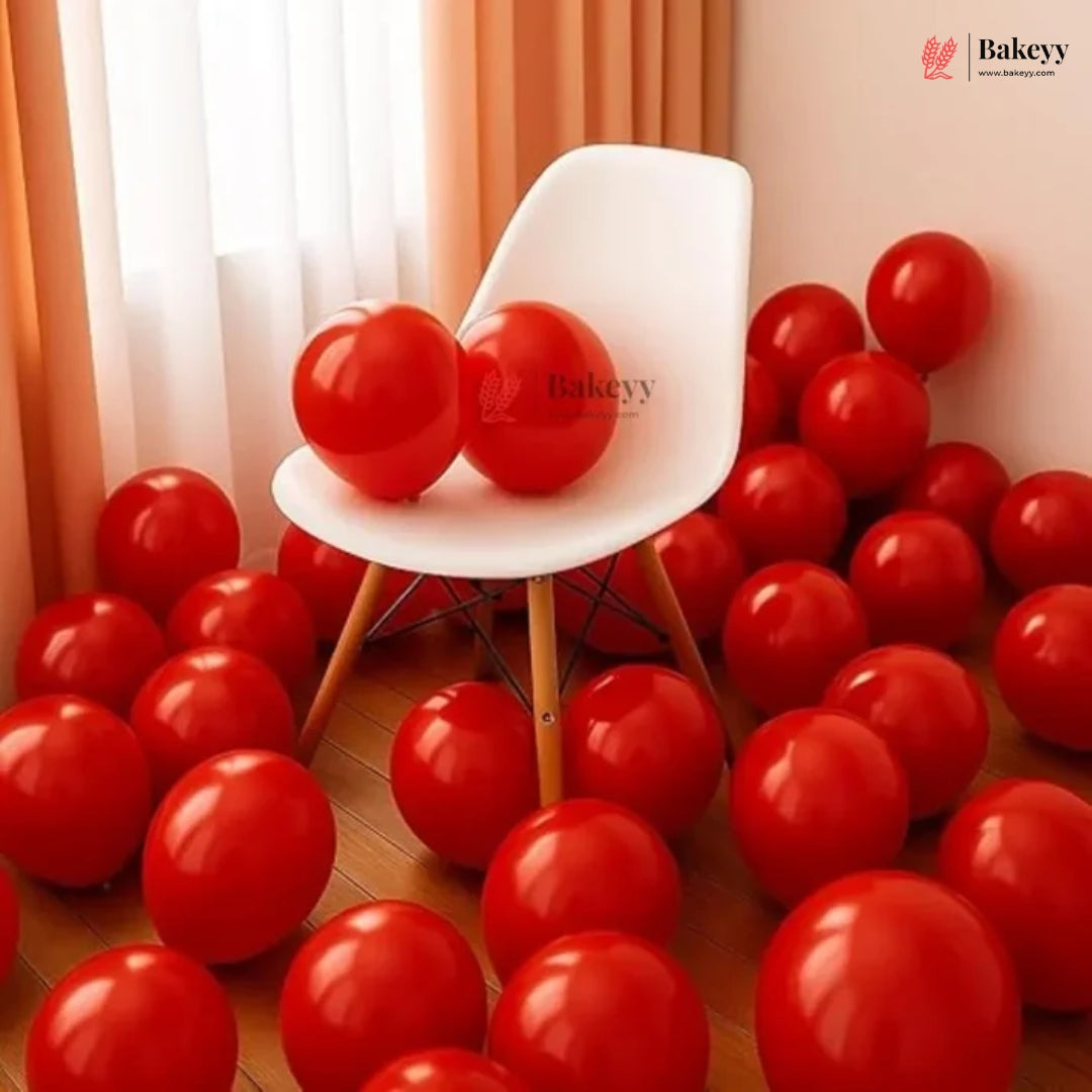 White chair surrounded by red balloons in a room with curtains.