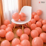 White chair surrounded by pink balloons in a room with curtains.