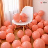 White chair surrounded by pink balloons in a room with curtains.