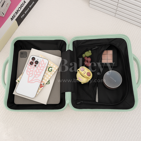 Open green travel case with phone, books, and small toys on a white surface.