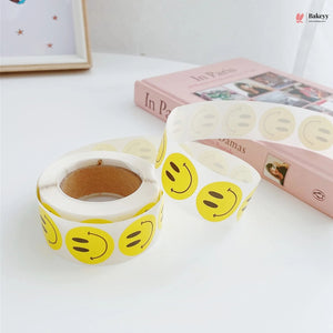 Rolls of yellow smiley face tape on a white surface with a pink book in the background.