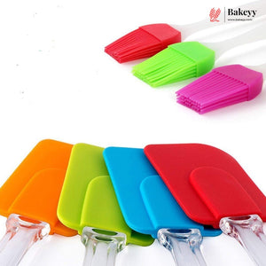 Six silicone pastry spatulas in orange, lime green, blue, red, and pink, shown with clear plastic handles on a white background. Three matching pastry brushes in red, green, and pink are displayed in the upper right, with the Bakey logo in the top right corner.