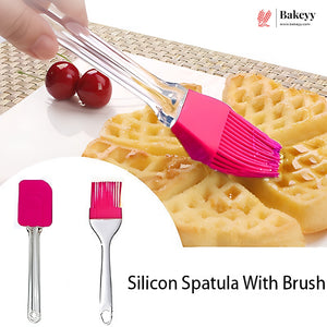 A silicone pastry brush with a bright pink silicone head and clear handle is shown being used to brush waffles with syrup. The image includes a circular inset showing the brush alone from two angles, with cherries and a woven placemat in the background.