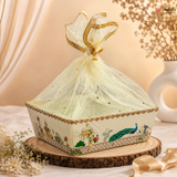 Decorative box with floral patterns and a gold ribbon on a wooden surface.