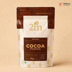 A 1kg stand-up pouch of 2m Brown Cocoa Powder, featuring a white and dark brown design with gold text and cocoa bean illustrations, set against a solid beige background.