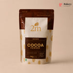 A 1kg stand-up pouch of 2m Brown Cocoa Powder, featuring a cream and dark brown design with gold cocoa bean illustrations, set against a solid beige background.