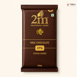 A 500g package of 2m Milk Chocolate 37% Cocoa Solids, shown against a light cream background. The packaging is dark brown with gold lettering and cocoa illustrations.