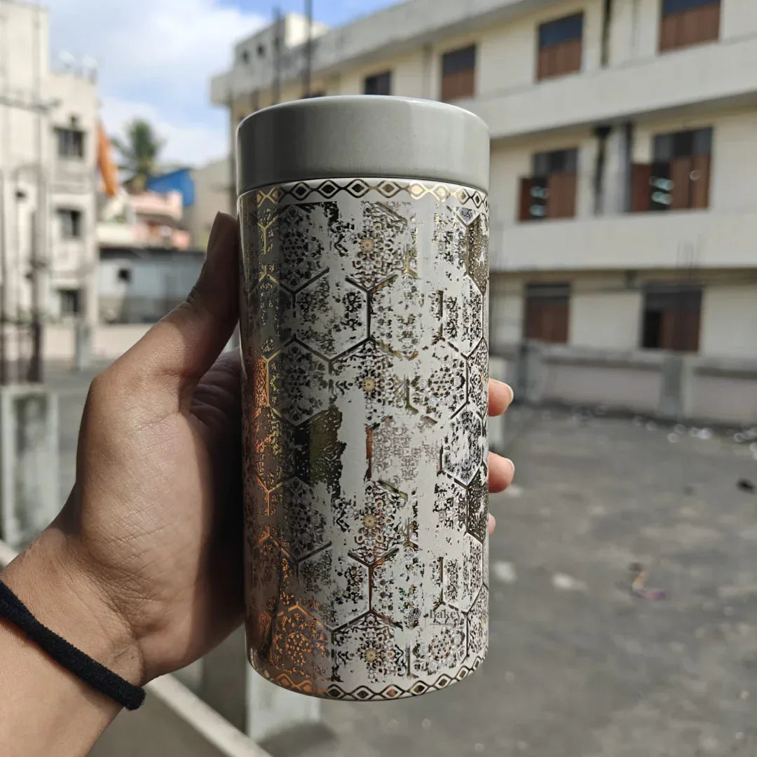 Hand holding decorative airtight jar with metallic geometric pattern, outdoor urban background