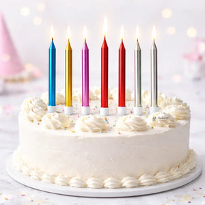 Bakeyy birthday cake with white frosting, colorful tall candles, and sprinkles