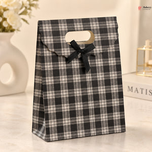 Black and white plaid gift bag with a bow on a light background