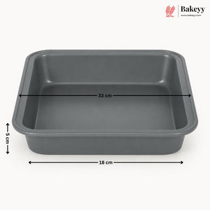 A dark gray rectangular baking pan with dimension lines indicating 33 cm length, 18 cm width, and 5 cm height, shown on a light gray background with the Bakeyy logo in the top right.
