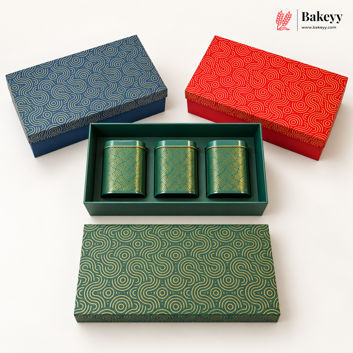 Three decorative rectangular boxes with matching lids are arranged on a white background. One box is open and contains three small cylindrical green tins with gold patterns.