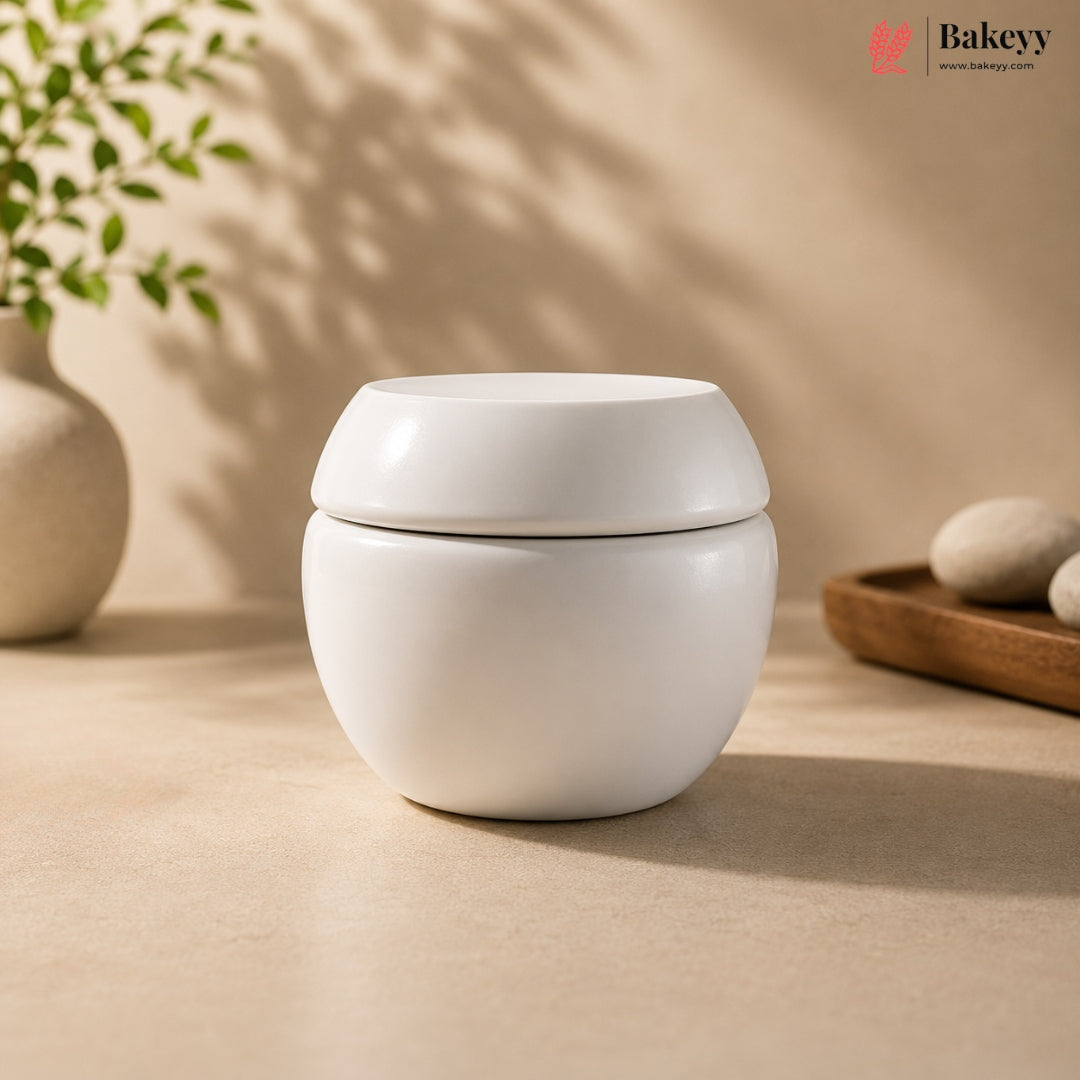 White ceramic container with lid on a beige surface, with 'Bakeyy' branding in the corner.