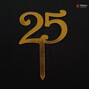 Gold metallic number 25 cake topper with a stick, shown on a black background. A Bakeey logo is visible in the top right corner.
