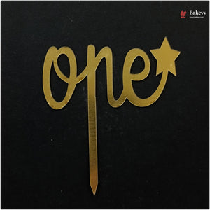 Gold metallic 'one' and star cake topper with a stick, displayed on a black background. A Bakeey brand logo is visible in the top right corner.