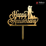 Gold acrylic 'Happy Anniversary' cake topper with a silhouette of a bride and groom on a black background, featuring a Bakeyy brand watermark in the top right corner.
