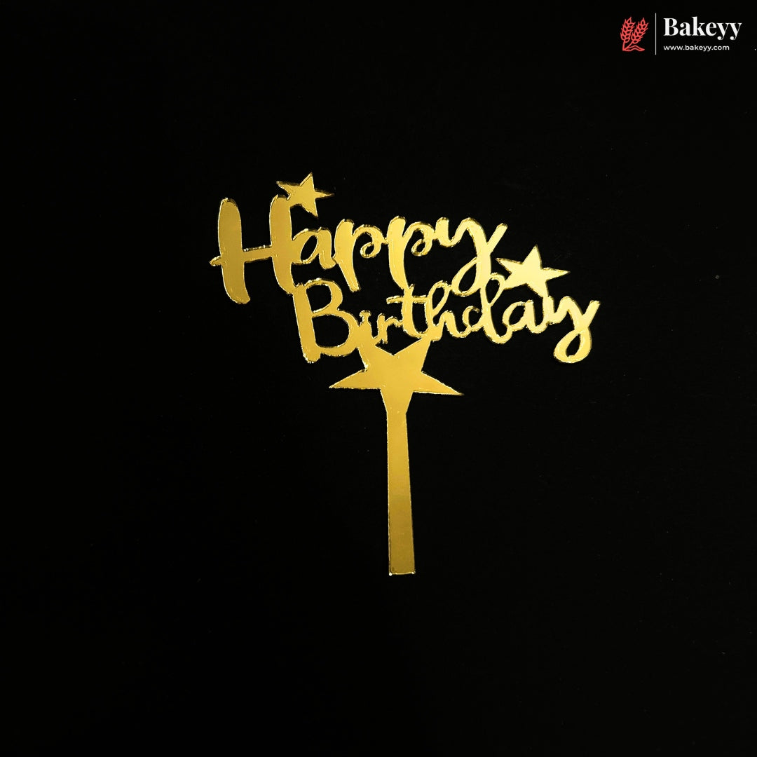 Gold 'Happy Birthday' cake topper with star accents and a stick, shown on a black background. A Bakeey logo is visible in the top right corner.