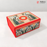A rectangular red gift box with ornate peacock and floral illustrations on the lid and sides, photographed on a clean white studio background. The Bakeyy logo appears in the top right corner.
