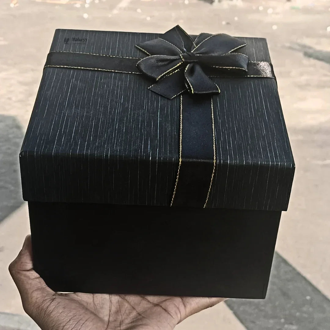 Black gift box with gold-trimmed ribbon bow for hamper or bakery packaging from Bakeyy.com