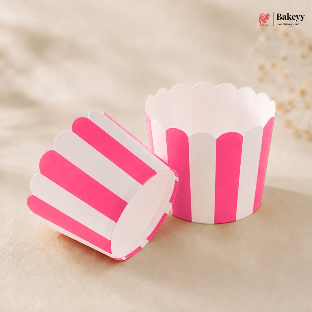 Two pink and white striped paper cupcake liners, one standing upright and one lying on its side, on a beige textured background with a Bakeey logo in the top right corner.
