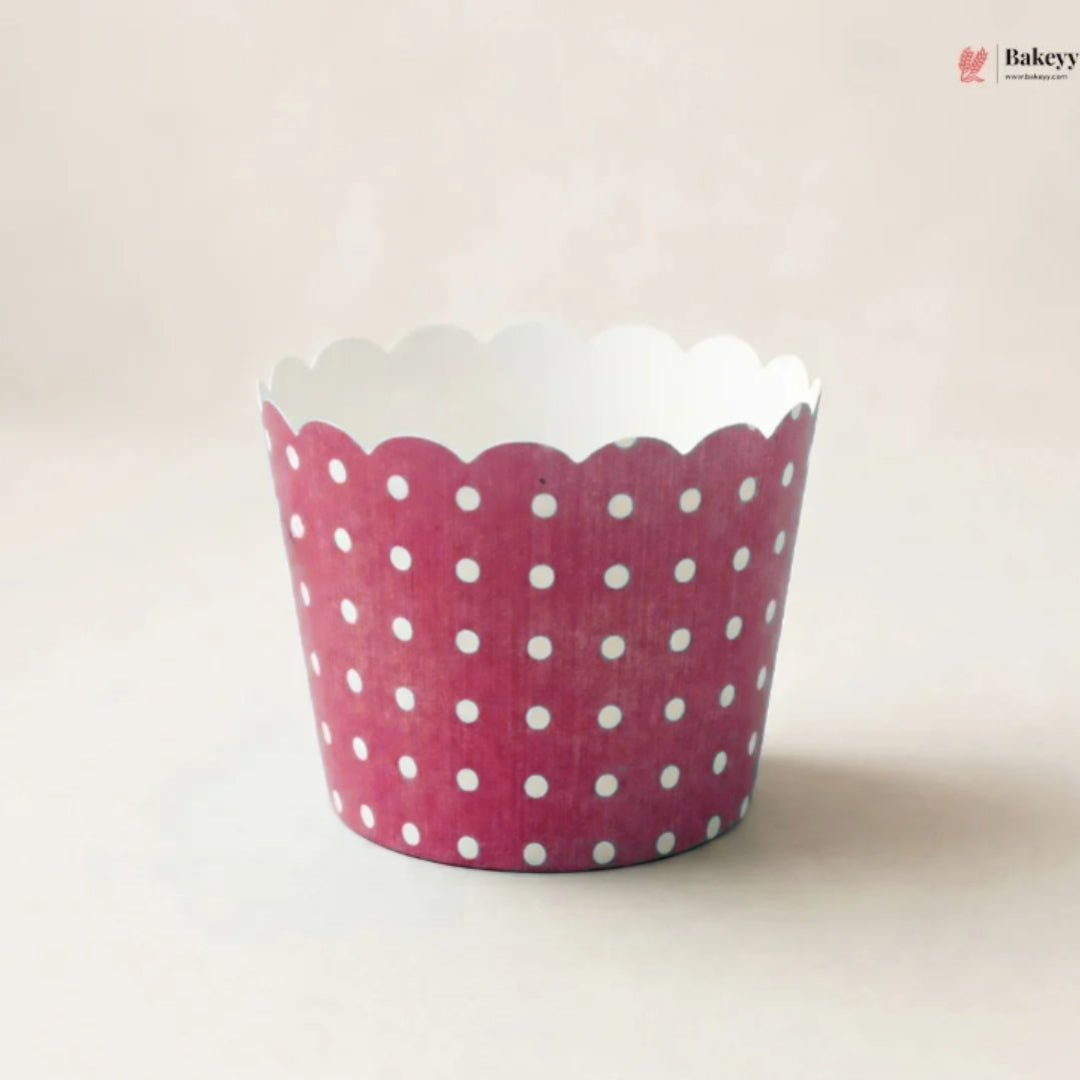 A single scalloped cupcake liner with a pink and white polka dot pattern, photographed on a light beige background.