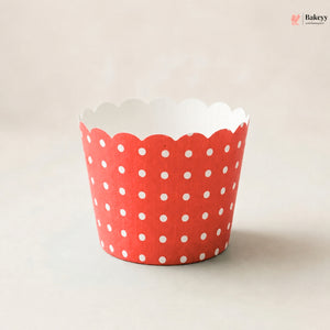 A single red paper cupcake liner with white polka dots and a scalloped edge, photographed on a plain light beige background. A Bakeey watermark is visible in the top right corner.
