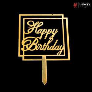 Gold metal Happy Birthday cake topper with a geometric frame design and stake, shown on a solid black background.