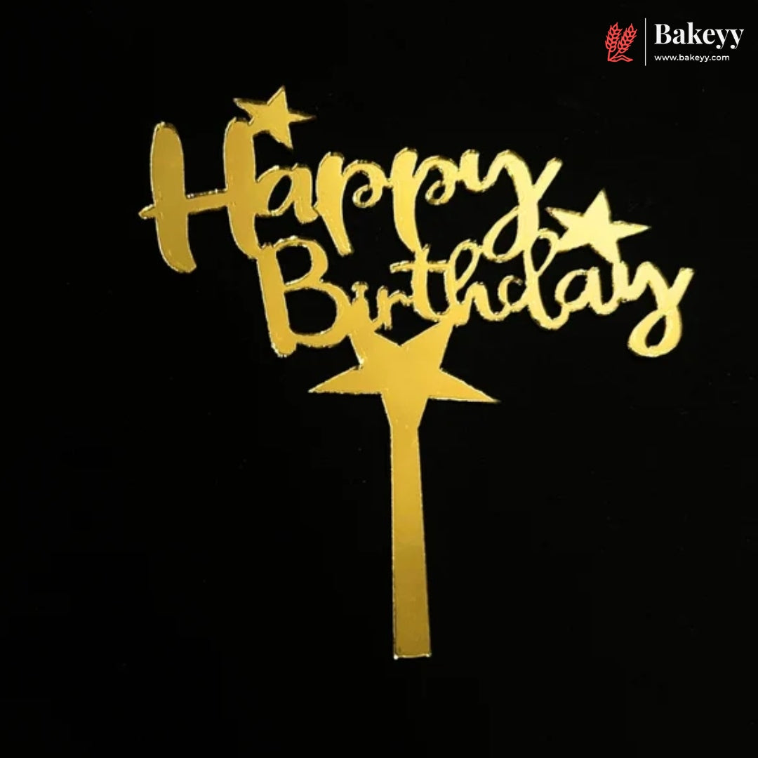Gold foil 'Happy Birthday' cake topper with star accents and a wand-shaped base, shown on a black background. A Bakeey logo watermark is visible in the top right corner.