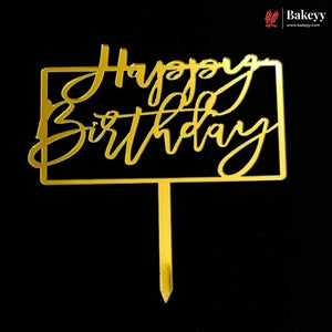 Gold metal 'Happy Birthday' cake topper with a rectangular frame and stick, shown on a black background. A Bakeey logo is visible in the top right corner.