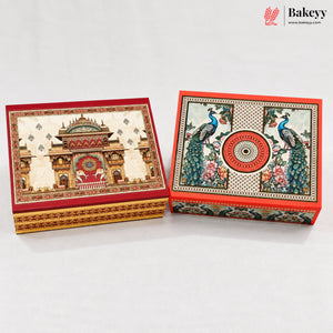 Two ornate rectangular gift boxes with decorative printed artwork, shown on a clean white background. One box features a palace motif in red and gold, and the other features peacocks and floral patterns with a red circular emblem.