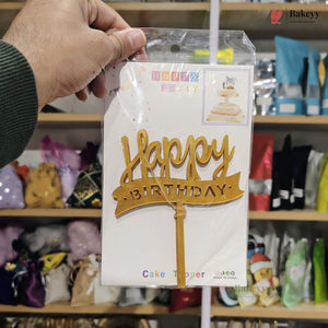 Hand holding a 'Happy Birthday' cake topper packaging in a store setting