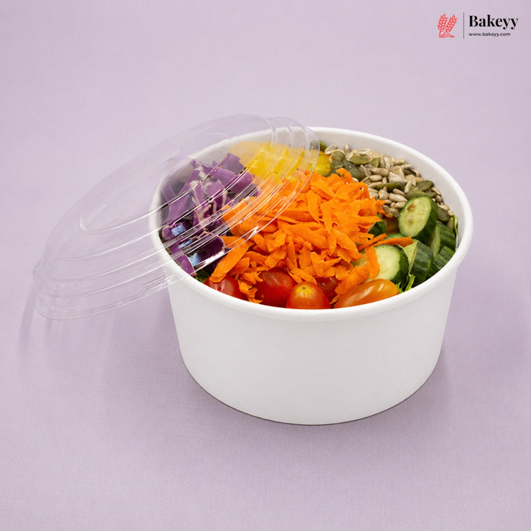 Salad in a white bowl with a transparent lid on a light purple background, featuring visible brands.