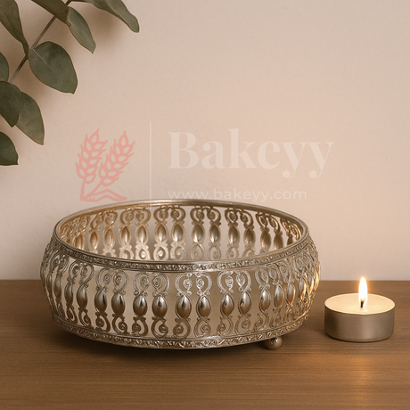 Decorative metal bowl with intricate patterns on a wooden surface next to a lit candle, with 'Bakeyy' branding.