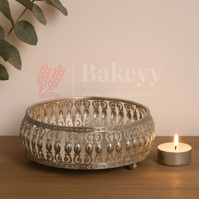 Decorative metal bowl with intricate patterns on a wooden surface next to a lit candle, with 'Bakeyy' branding.