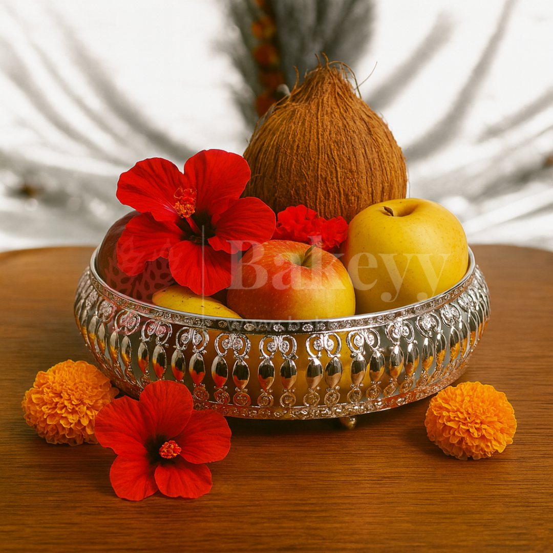 Decorative silver bowl with fruits and flowers on a wooden surface