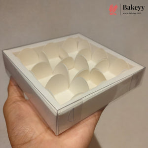 A hand holding a square white cardboard box with multiple curved paper cup insert compartments, shown against a plain beige background with a Bakeyy watermark in the top right.