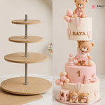 Three-tiered cake with teddy bears and balloons on a wooden cake stand.